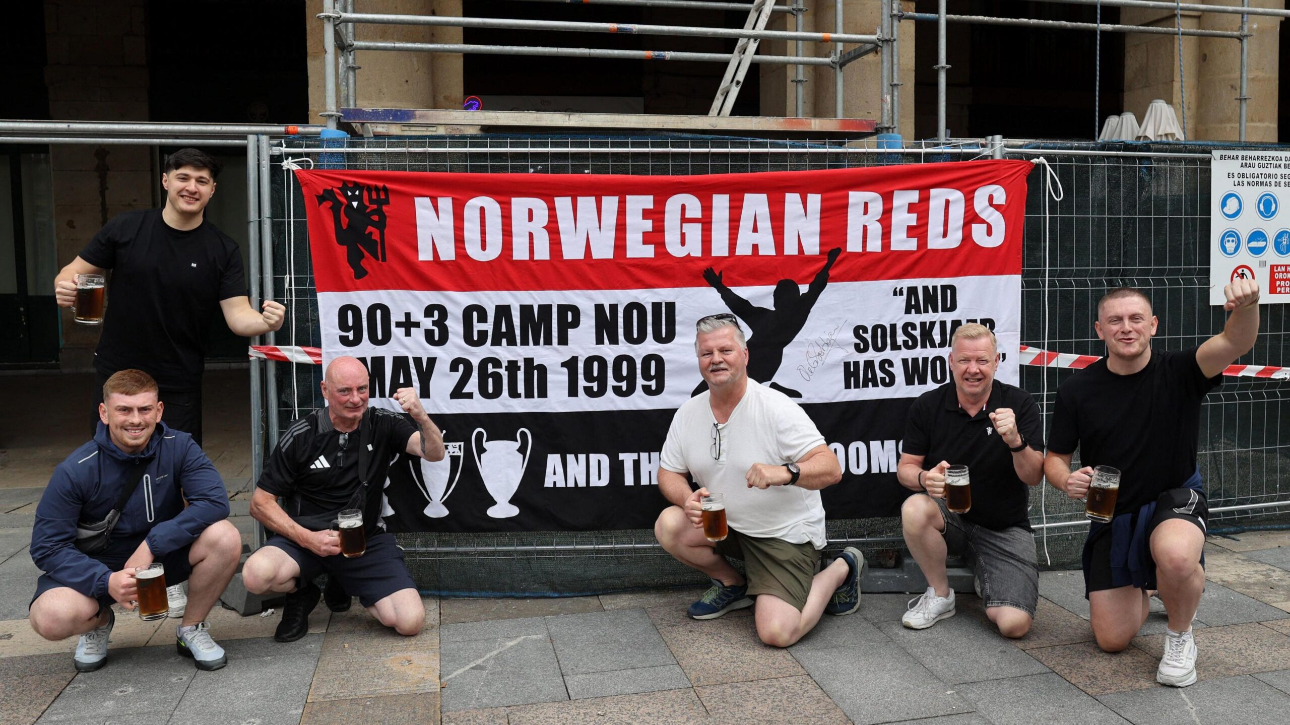 Manchester United fans in Bilbao in front of a banner commemorating their 1999 Champions League win
