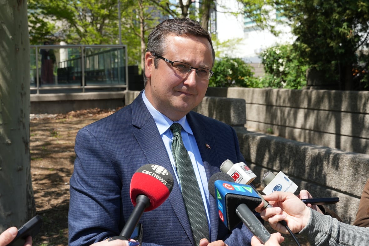 Man in blue suit surrounded by microphones