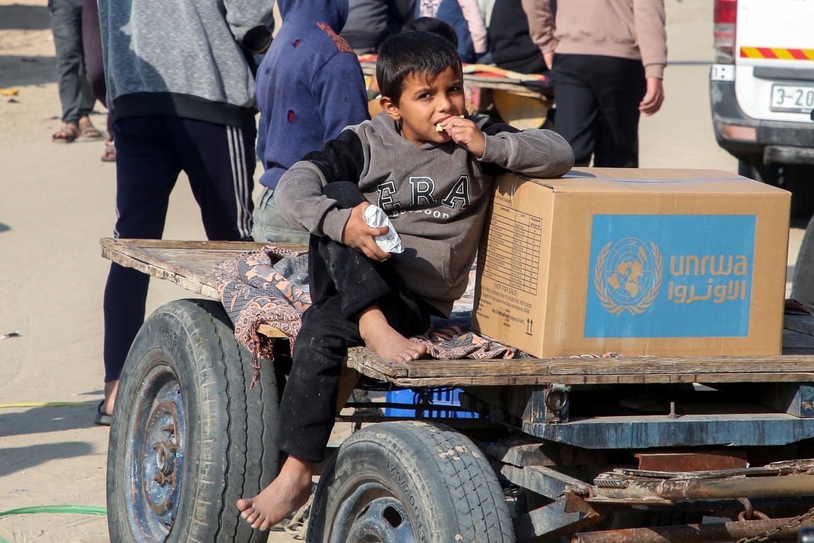 A Palestinian boy sits beside an aid box provided by UNRWA outside a distribution point, amid a ceasefire between Israel and Hamas, in Khan Younis in the southern Gaza Strip, February 4, 2025.