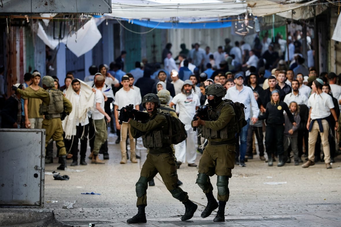 Israeli soldiers react as Israeli settlers gather during a scuffle with Palestinians in Hebron in the Israeli-occupied West Bank November 19, 2022.