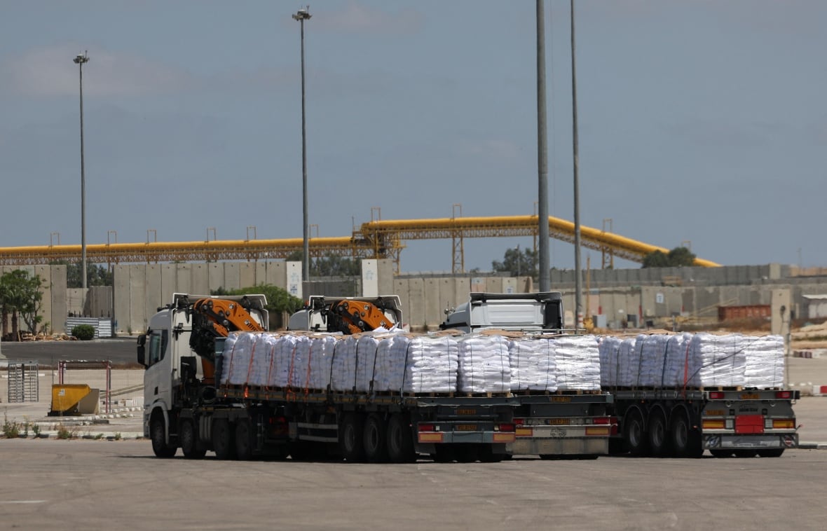 Trucks carrying aid enter through a crossing.