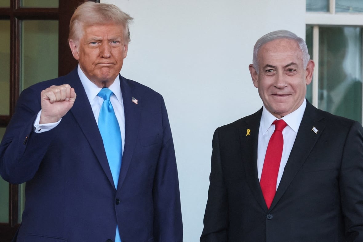 Donald Trump raises his fist, standing next to Benjamin Netanyahu.