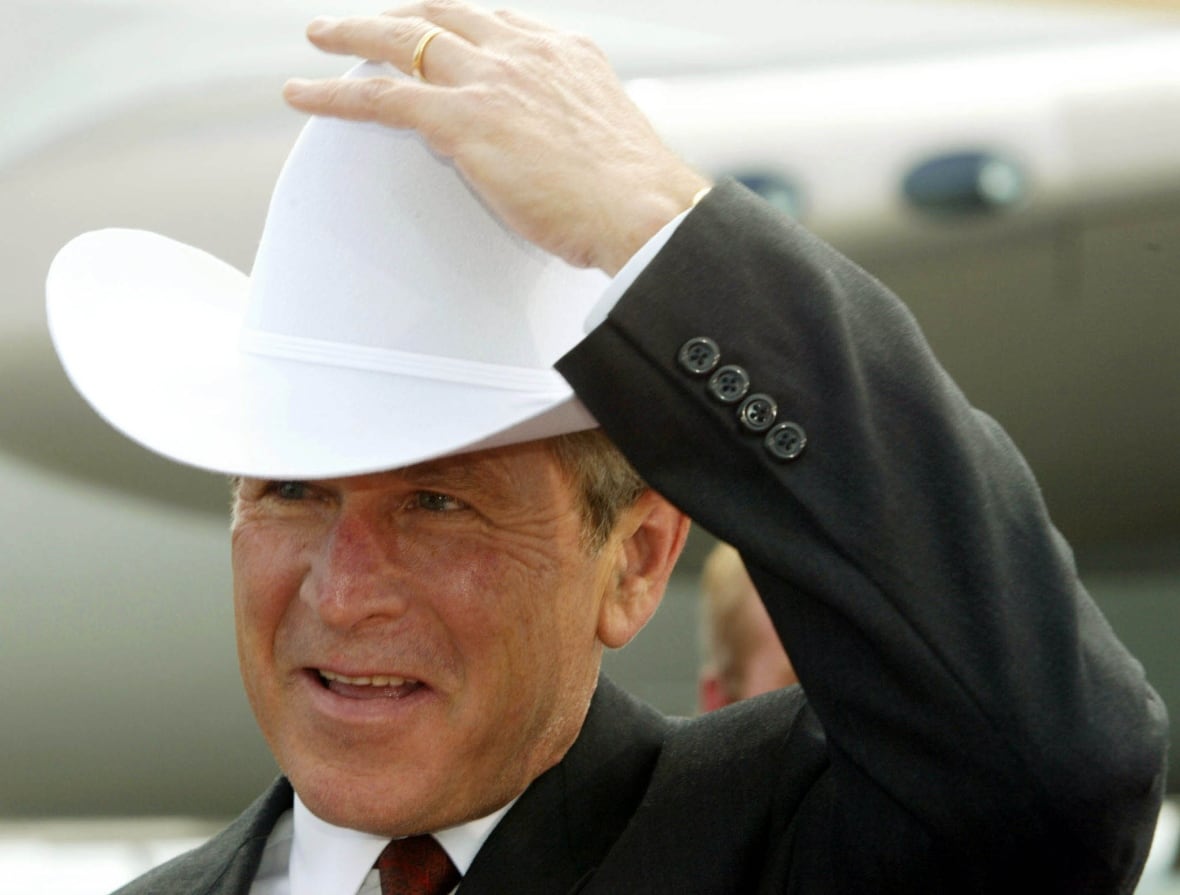 U.S. President George W. Bush puts on a cowboy hat presented to him by Calgary Mayor Dave Bronconnier, on June 25, 2002.