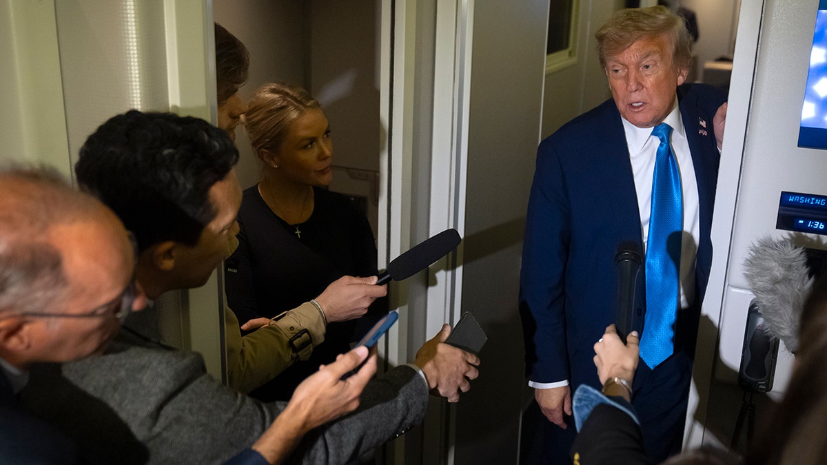 President Donald Trump in doorway inside Air Force One speaking with reporters