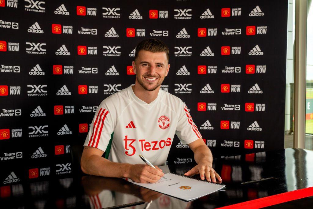 Mason Mount smiles towards the camera while signing his Manchester United contract.