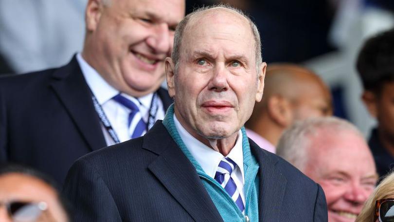 Michael Eisner stands in the crowd at Portsmouth, in shirt and tie, watching on intently