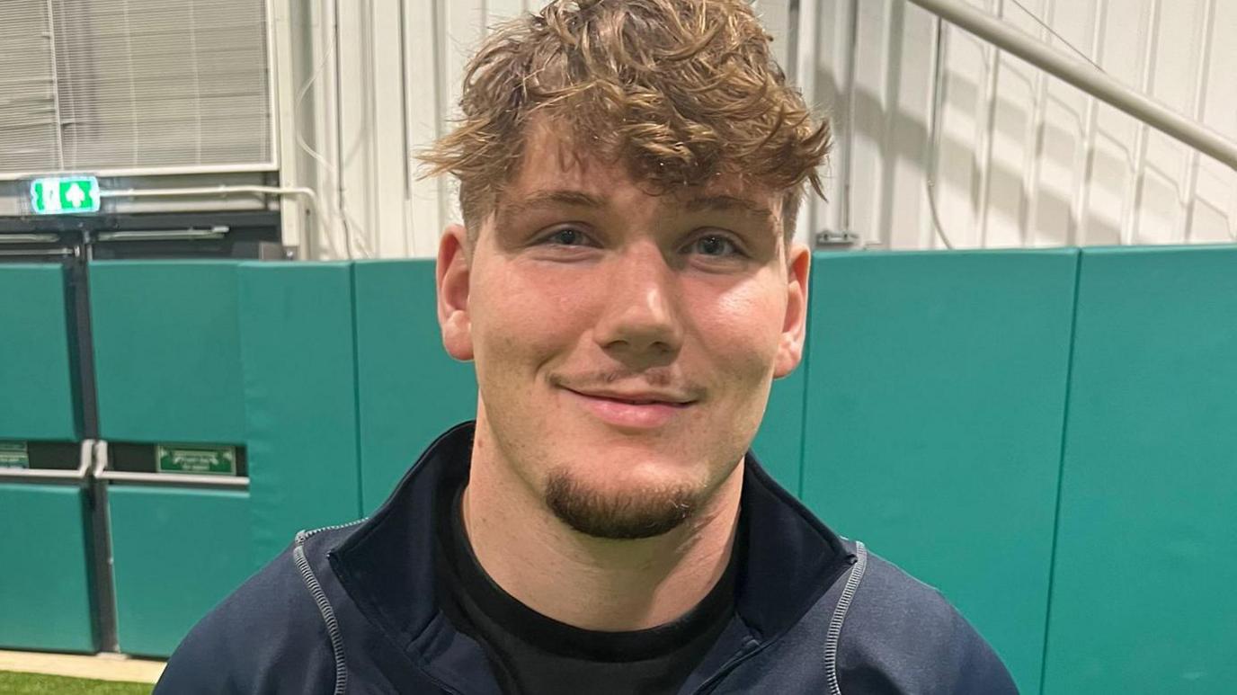 NSB's Jack Lewis wears a blue collared top and is looking at the camera