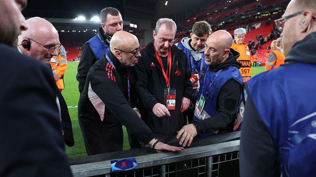 Ground staff and members of Liverpool investigate the board on which Noa Lang of Galatasaray suffered an injury
