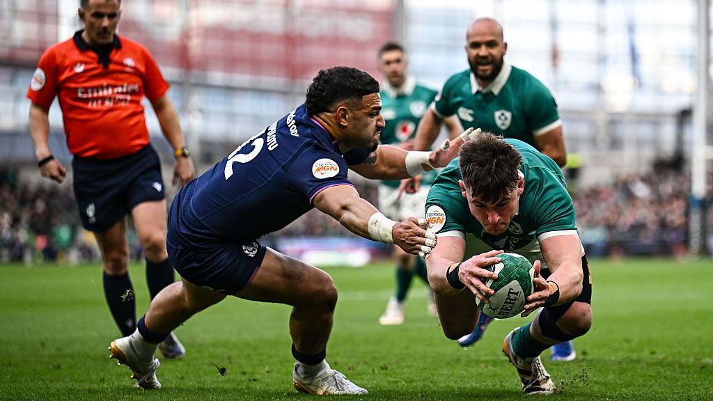 Dan Sheehan dives over to score Ireland side's second try with the ball between his hands despite the close attentions of Sione Tuipulotu