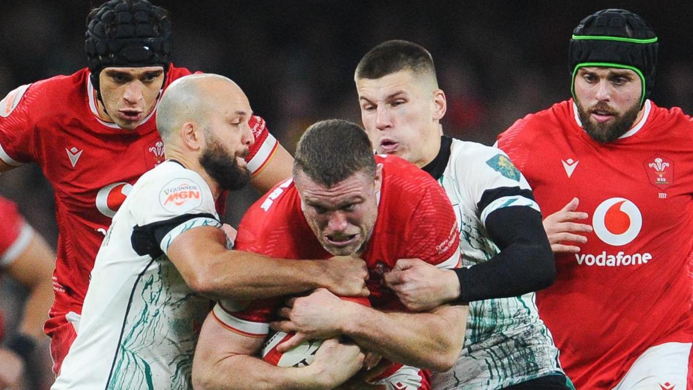 Will Rowlands being tackled by Ireland's Jamison Gibson-Park and Sam Prendergast