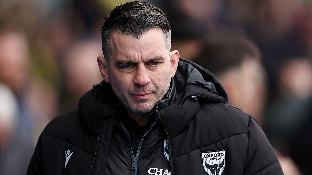 Oxford boss Matt Bloomfield looking serious wearing a black coat with the Oxford United club badge on it