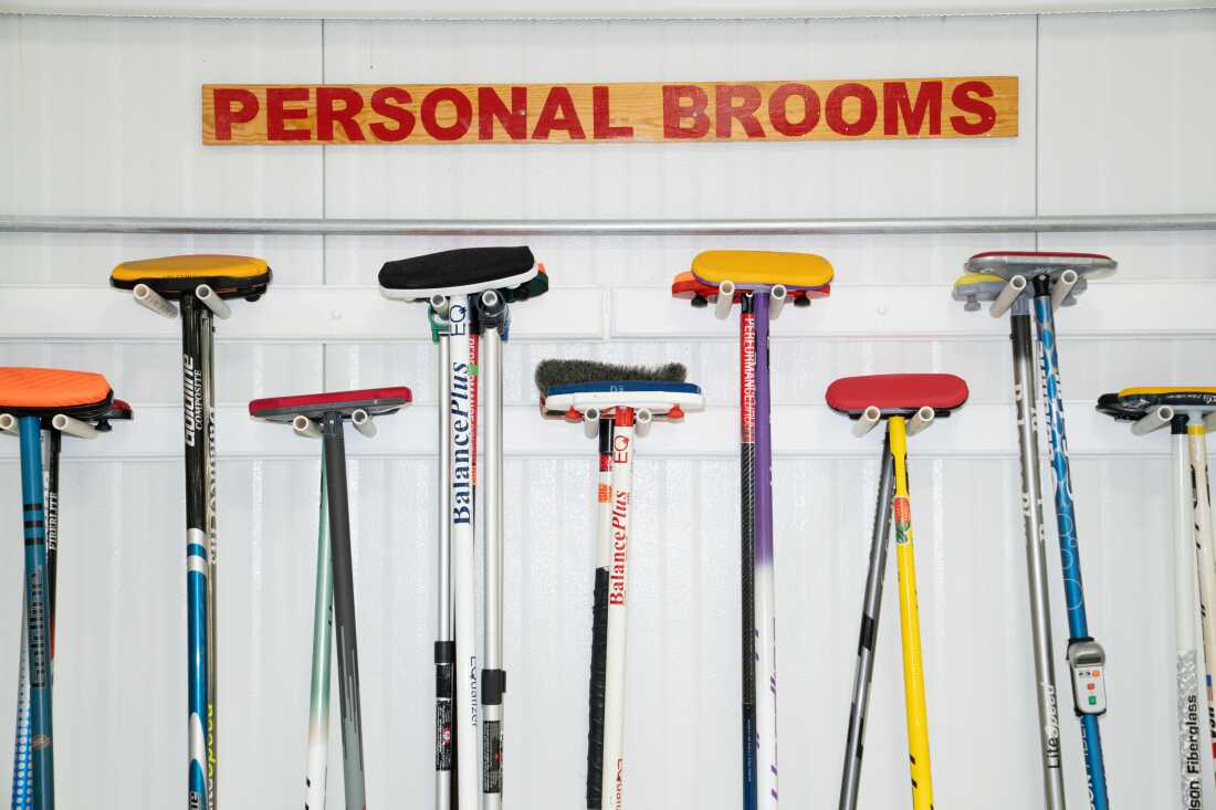 Brooms hang on the wall at the Potomac Curling Club under a sign that says "Personal Brooms."