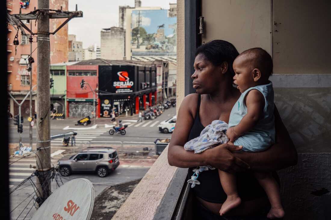 Janaina Xavier, a community leader, holds her son while looking out the window of the building where she lives with six of her 10 children in an occupation near the Cracol&acirc;ndia district in S&atilde;o Paulo, Brazil, on April 23, 2024. She currently serves as a council member for the Coordination of Policies for the Homeless Population and advocates for the rights of people living in and around Cracol&acirc;ndia, one of the city&rsquo;s most stigmatized areas. I chose this image because it reflects how women living in marginalized urban spaces are shaping public policy and grassroots resistance. Janaina Xavier&rsquo;s leadership connects motherhood, community organizing and political advocacy in one of S&atilde;o Paulo&rsquo;s most contested territories. This image has not been previously published and was not produced with grant funding.