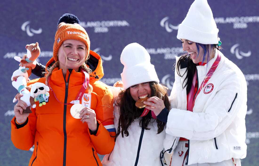 Kate Delson (C) and Brenna Huckaby (R) of Team United States pose for a photo with their flags on the podium during the medal ceremony for the Para Snowboard Women's Banked Slalom SB-LL2.