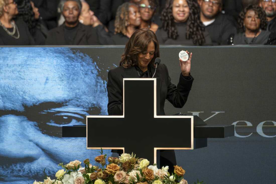 Former Vice President Kamala Harris holds a campaign button from the Rev. Jesse Jackson&rsquo;s 1988 presidential run while speaking during Jackson's public homegoing service at the House of Hope in Chicago on Friday.