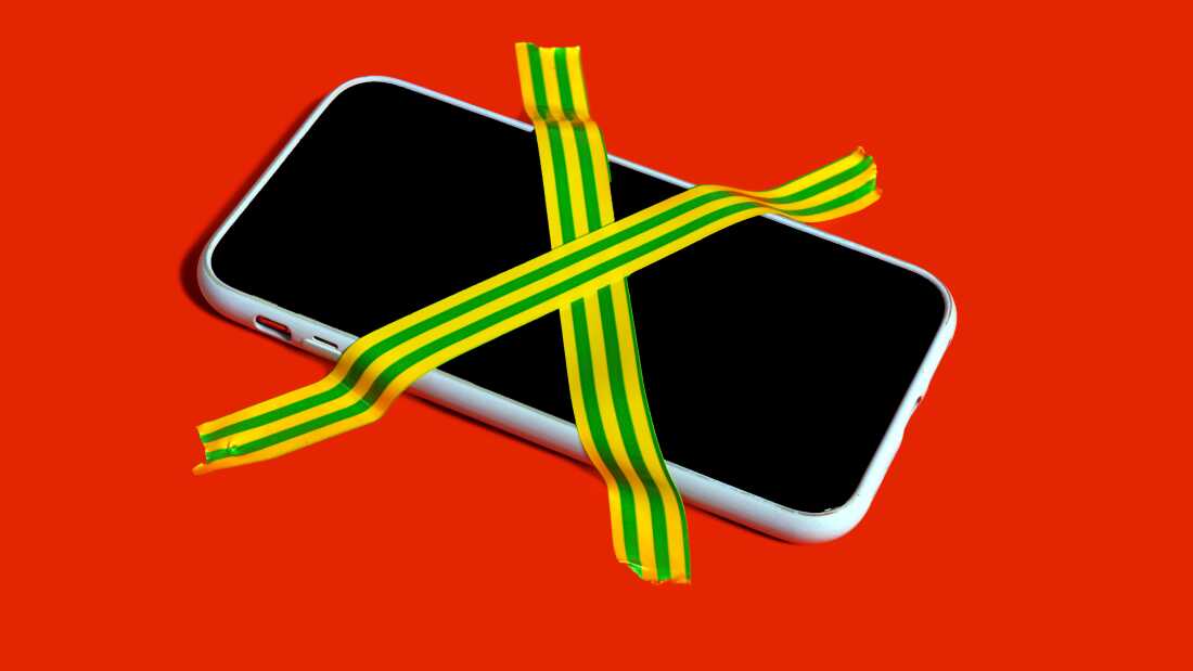 Colorful still life of a banned smartphone with cross-hatched adhesive tape.