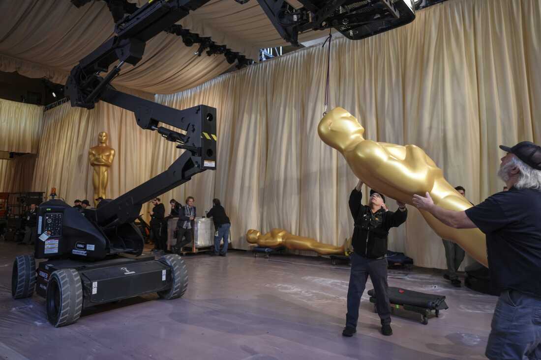 Workers set up an Oscar statue in the red carpet area before the 2025 Oscar awards.